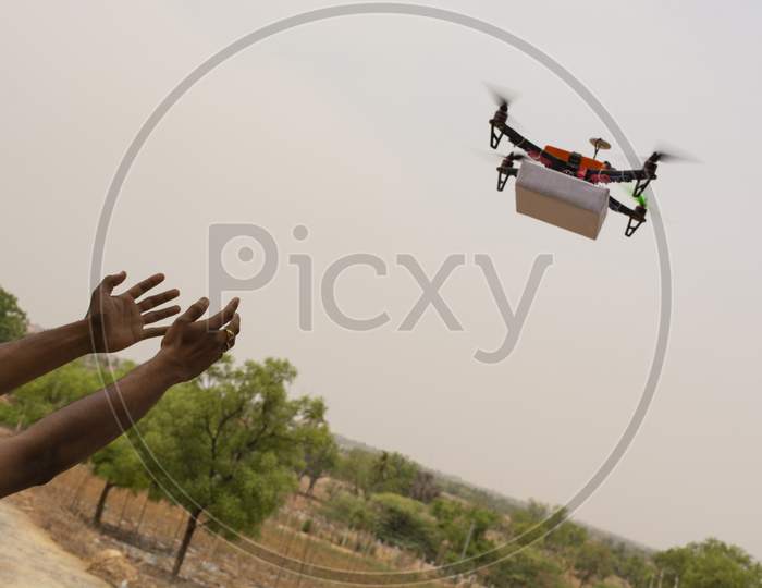 Assembled Drone Quadcopter Delivering A Package And Hands Receiving The Parcel