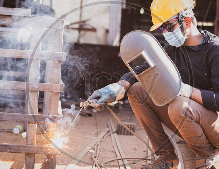 A Young Welder doing welding with a Welding Helmet and Mask during Corona Virus Pandemic