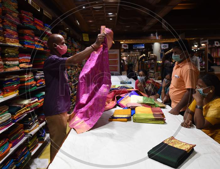 A Salesman Wearing A Face mask Shows A Saree To Customers At A Textile Garment Shop in Chennai, Tamil Nadu