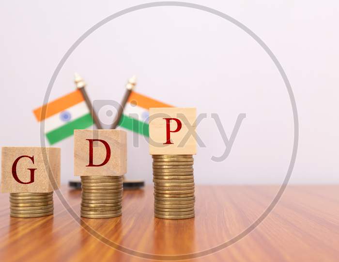 Gdp Or Gross Domestic Product In Wooden Block Letters On Coins In Increasing Order With Indian Flag As A Background.