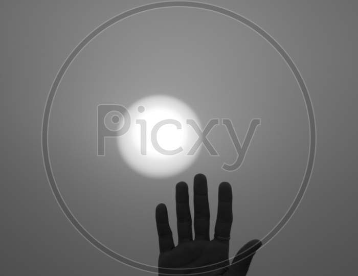 A Human Hand with Sun in the Background in Monochrome