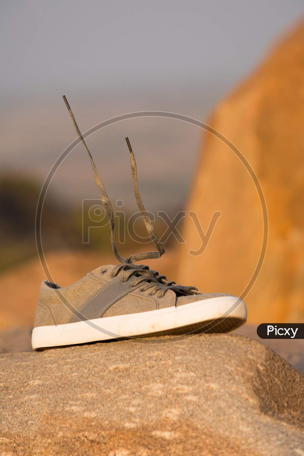 Stylish Men Olive Green Sneakers Or Regular Shoes On Top Of The Mountain With Levitating Shoelace