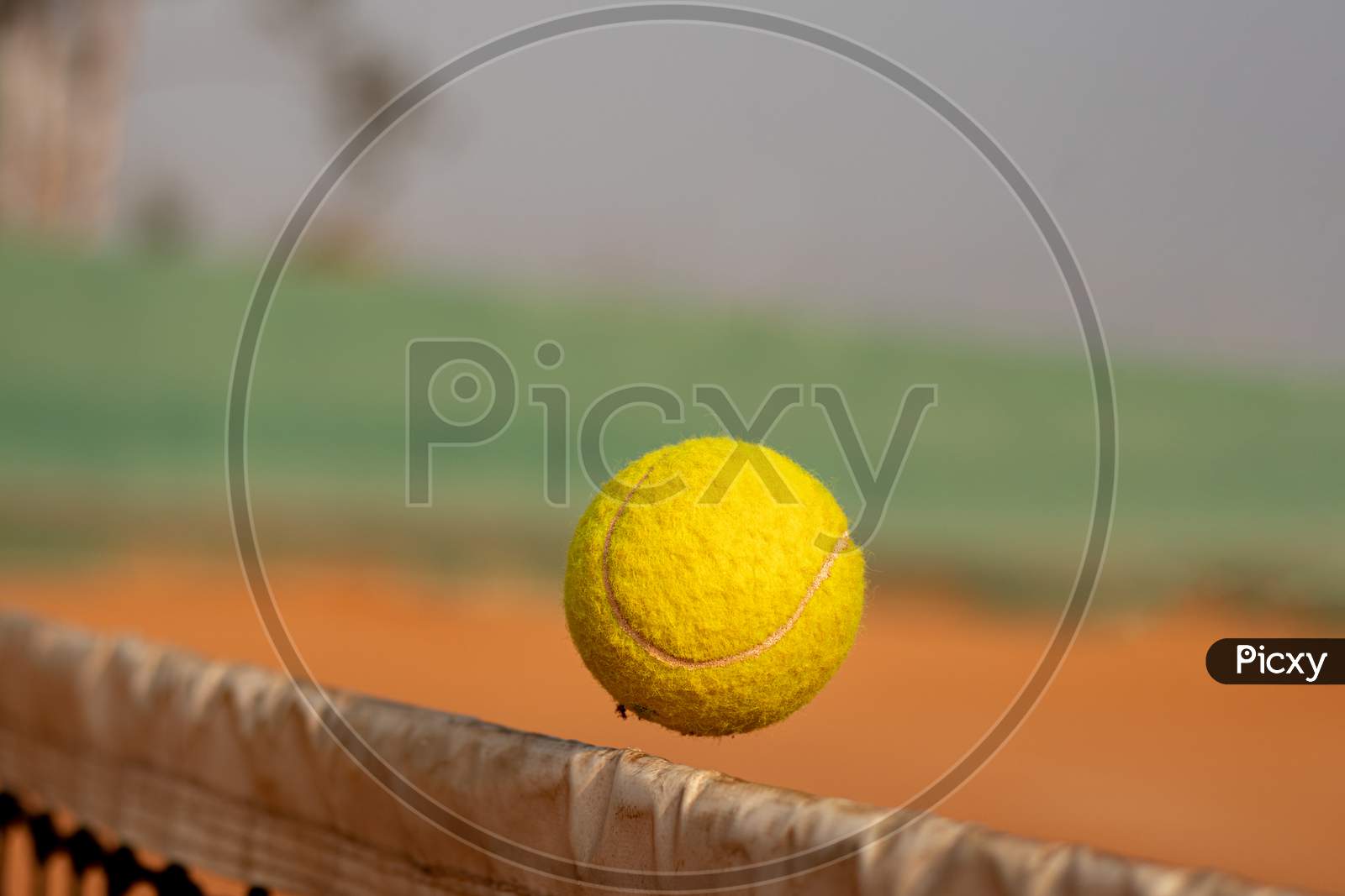 Close up shot of a Tennis Ball passing the Net in a Tennis Court