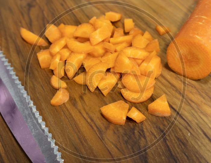 Close Up Of Chopped Carrots With Knife On Wood Table.