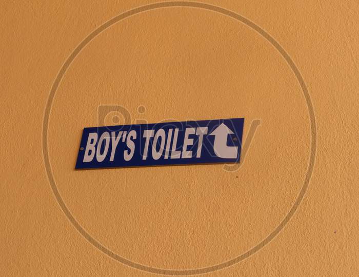 Direction Showing Of Boys Toilet On Wall At College