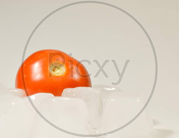 A tomato on the ice Cubes isolated with white background