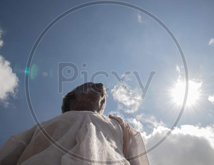 Low Angle View Of A Tribal Indian Farmer Below The Sun During Hot Sunny Day.