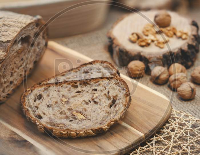 Two slices of walnut bread with other walnuts next to it.