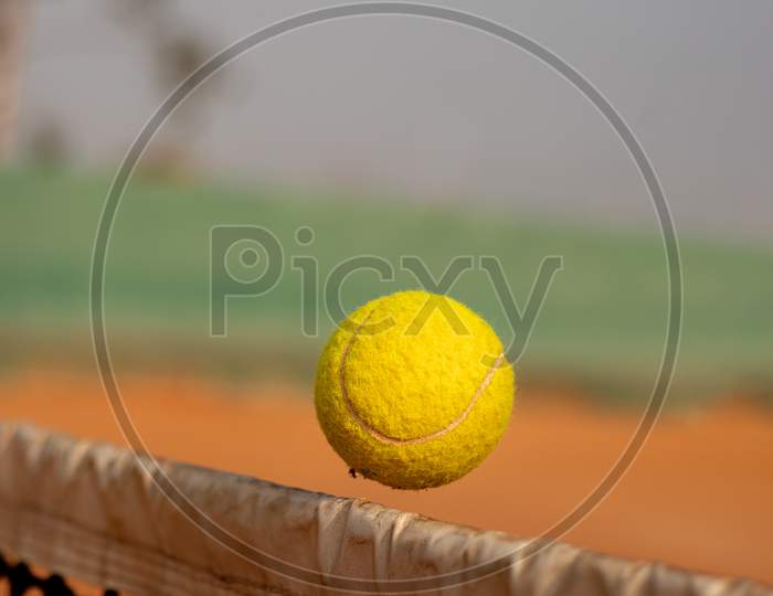 Close up shot of a Tennis Ball passing the Net in a Tennis Court