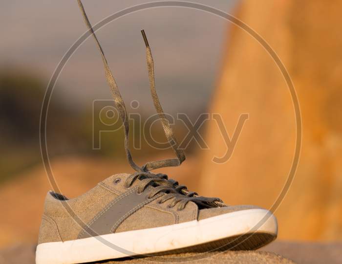 Stylish Men Olive Green Sneakers Or Regular Shoes On Top Of The Mountain With Levitating Shoelace
