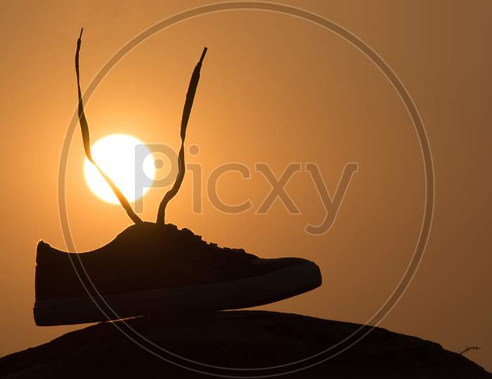 Silhouette Of A Shoe With Sun In Background