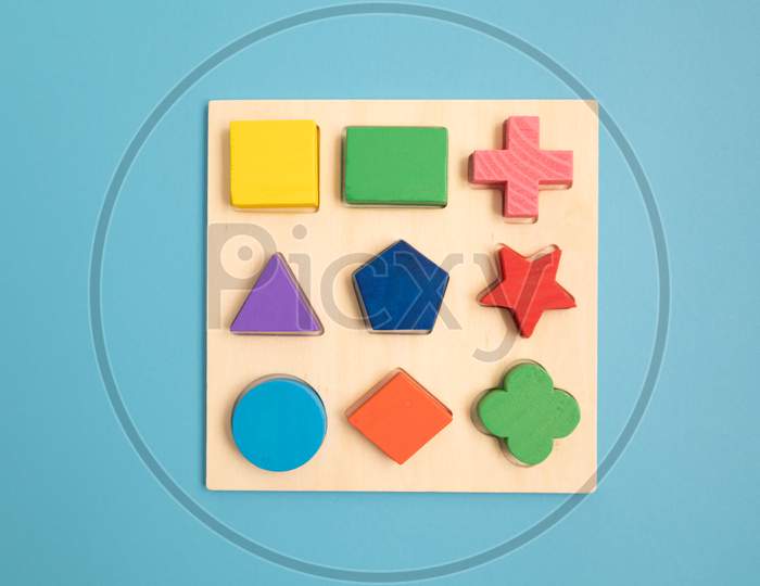 Top View Colorful Wooden Building Blocks With Different Shapes For Developing And Entertainment Of Children On Blue Background.