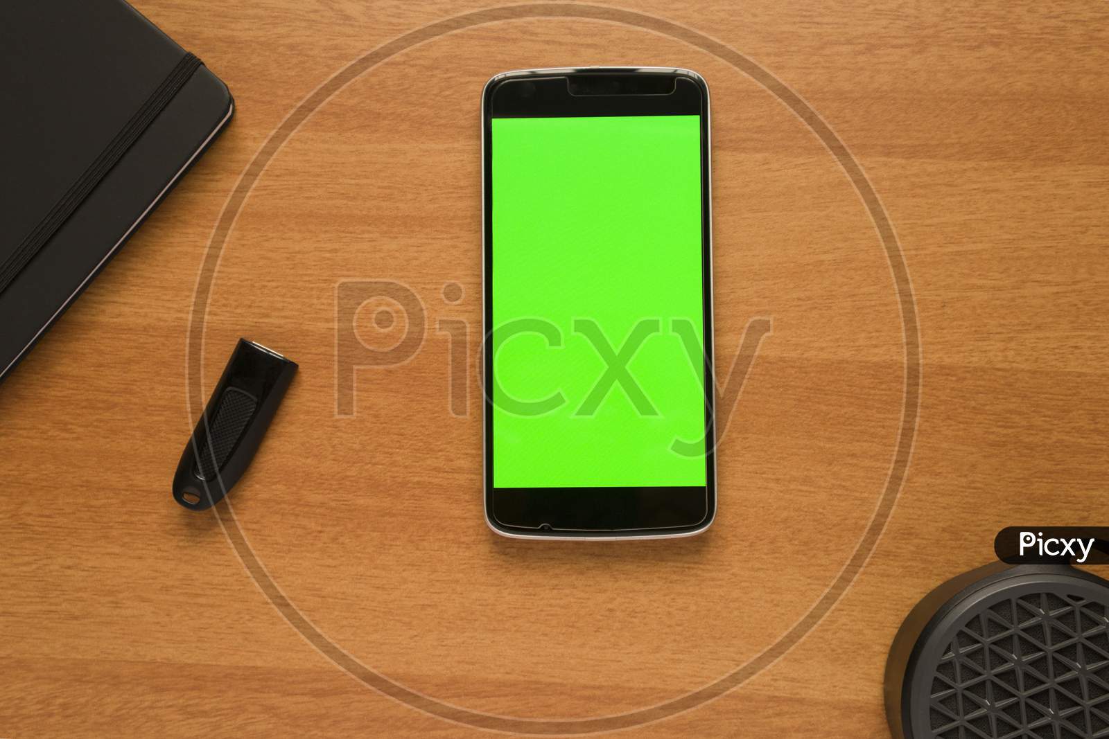 Smartphone With Green Screen Mock Up On Table With Bluetooth Speaker, Pendrive And Diary Book