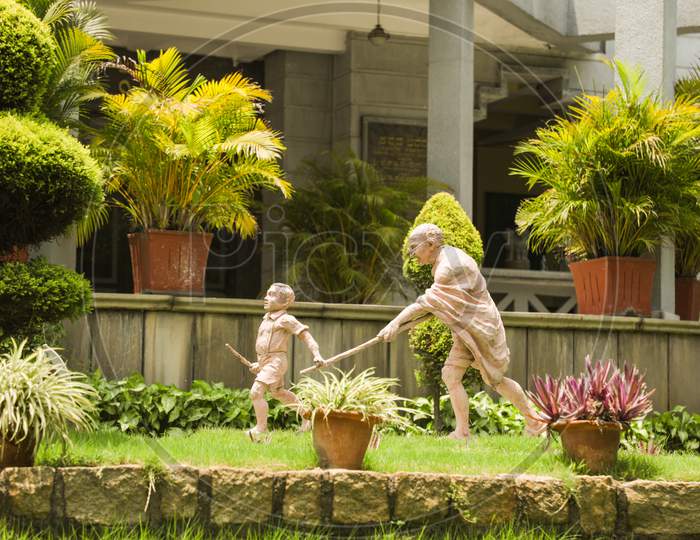 Sculpture Of Mahatma Gandhi And Child, Child Moving By Holding The Stick Of Mahatma Gandi At Bengaluru, India.