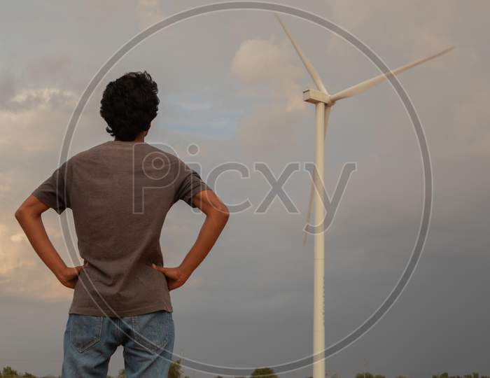 Back View of a Young Person Watching A Windmill