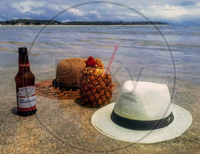 Concept Of Relaxing Showing Hats, Pineapple Juice With Straw And Abudweiser