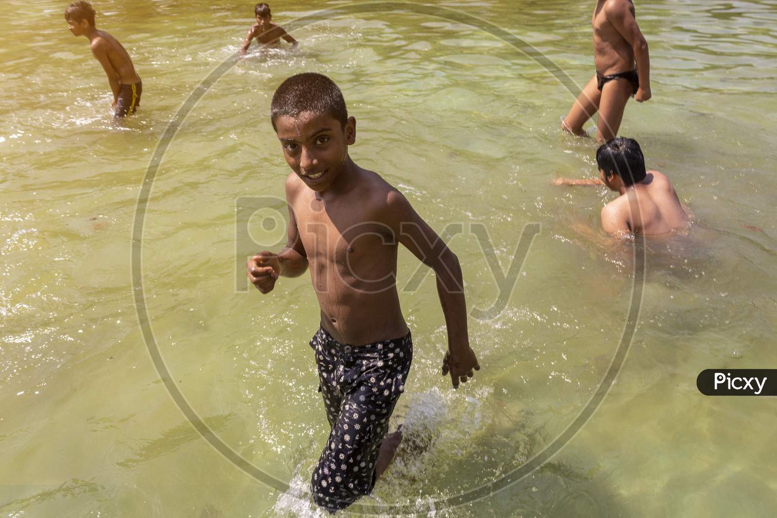 Delhi, New Delhi, India - May 26 2020: Happy Asian Kids Playing In A Lake Near India Gate In The Hot Summer. Cheerful And Carefree Children.