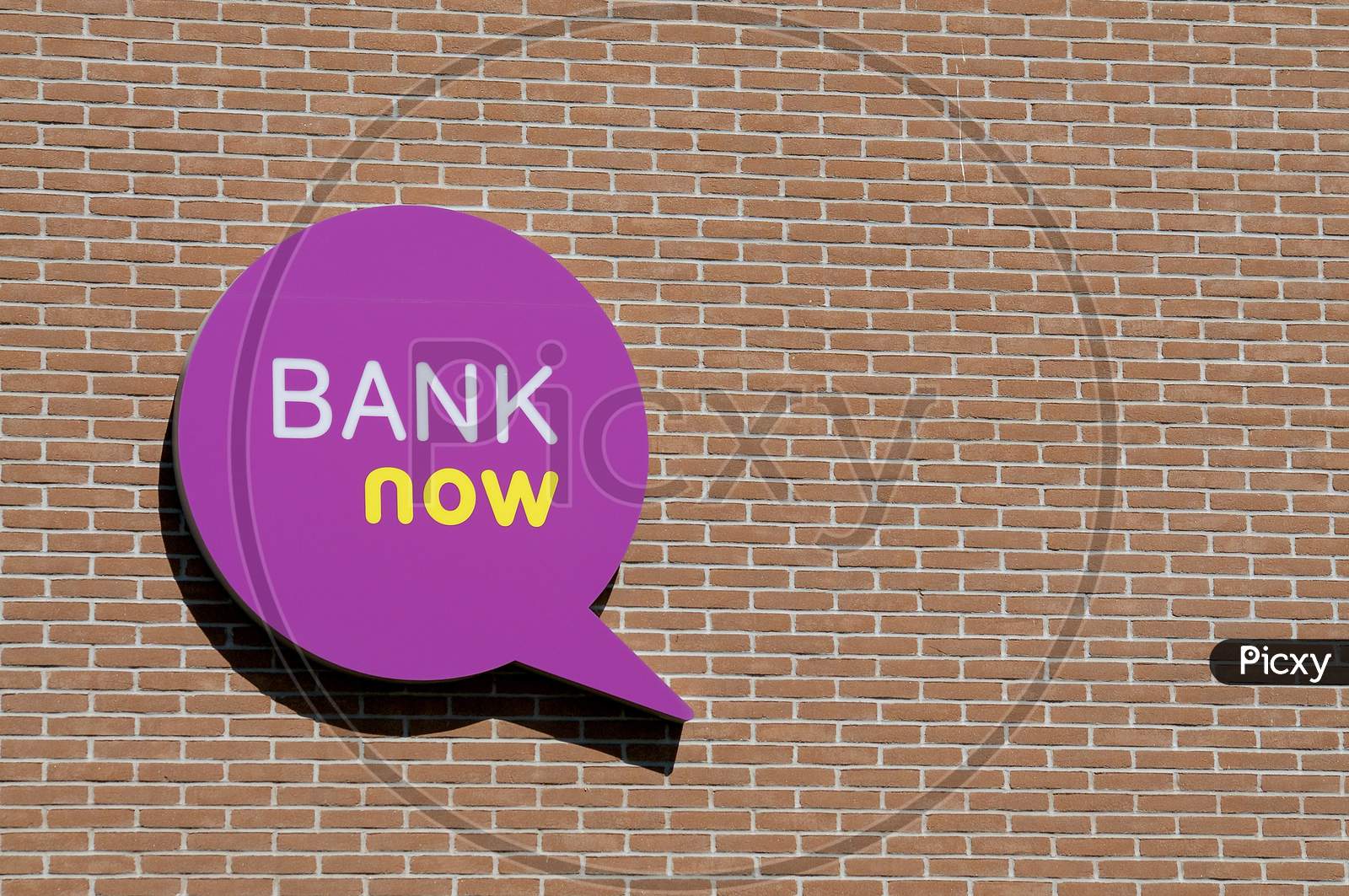 Bank Now Company Logo Hanging On A Brick Wall