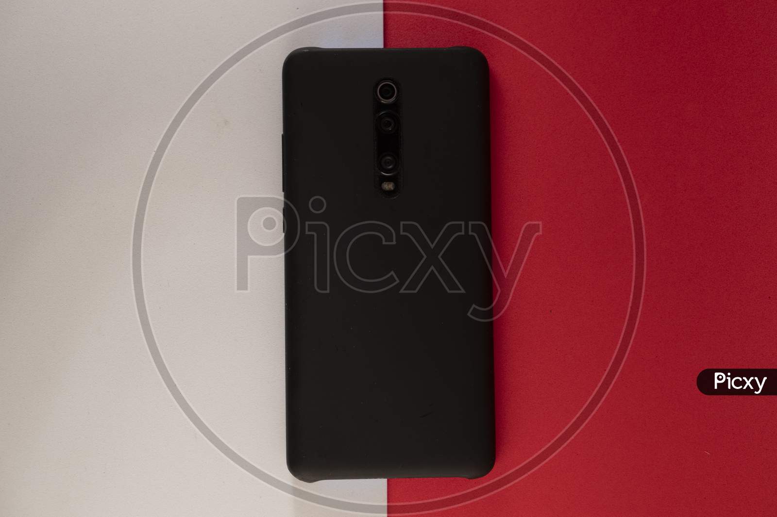 Smart phone or mobile phone with black phone cover on red and white background .