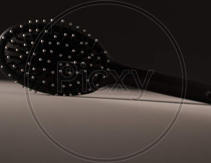 Black hair brush against white and black background. Photo has empty space for text.