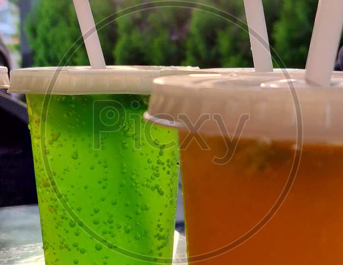 Picture Of Two Glass Of Soda With Straw And Trees On The Background.