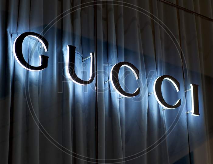 Illuminated Gucci Sign With Blue Curtain Background