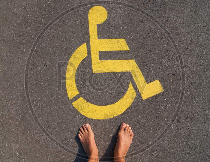 Man Standing In Front Of A Disable Handicap Parking Sign