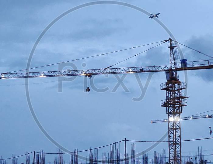 Silhouettes Of Tower Cranes Against The Evening Dark Sky. House Under Construction. Construction Site.