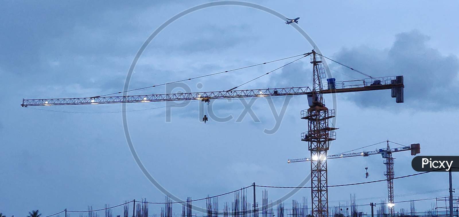 Silhouettes Of Tower Cranes Against The Evening Dark Sky. House Under Construction. Construction Site.