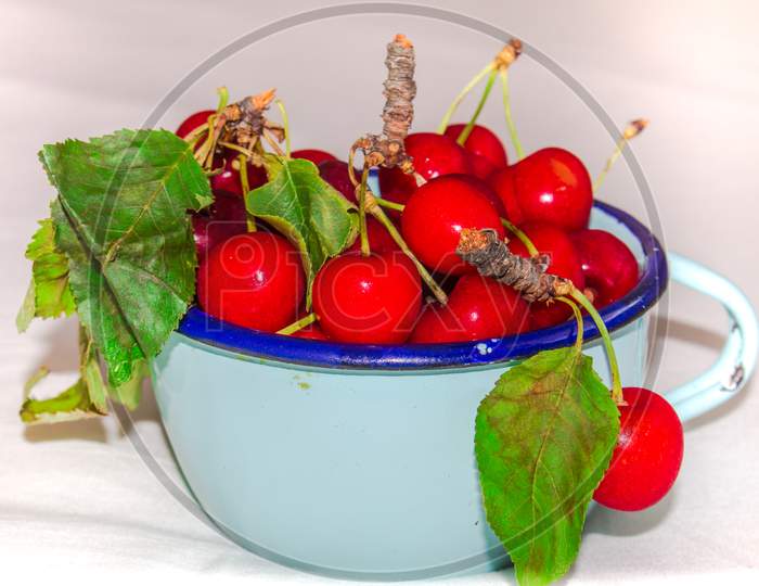 Red Cherries. Close up of pile of ripe cherries with stalks and leaves. Large collection of fresh red cherries. Ripe cherries background.