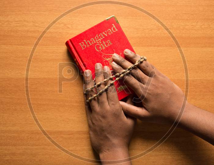 Holding Bhagavad Gita With Hands On Textured Background