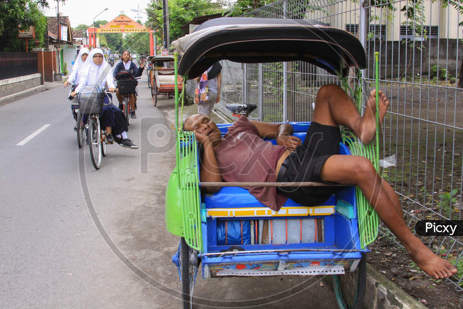 Rickshaw Driver Sleeping On The Job In Indonesia
