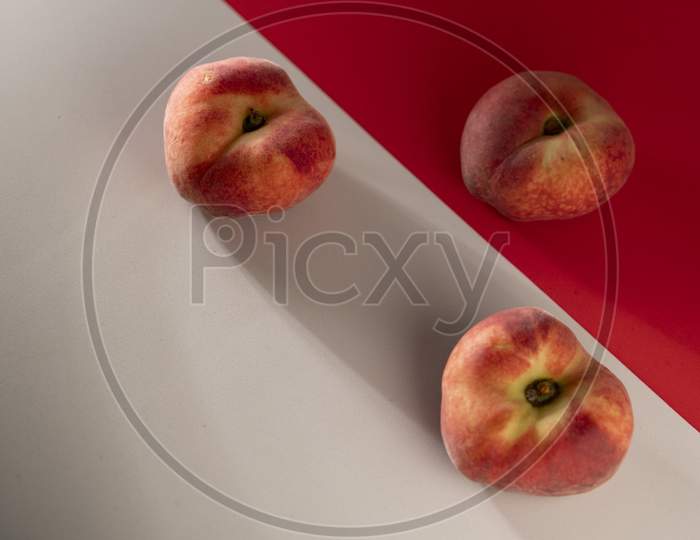 Juicy red peach on a red and white background.