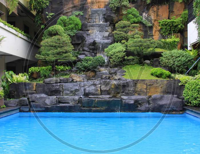 Waterfall And Plants Next To Swimming Pool Design