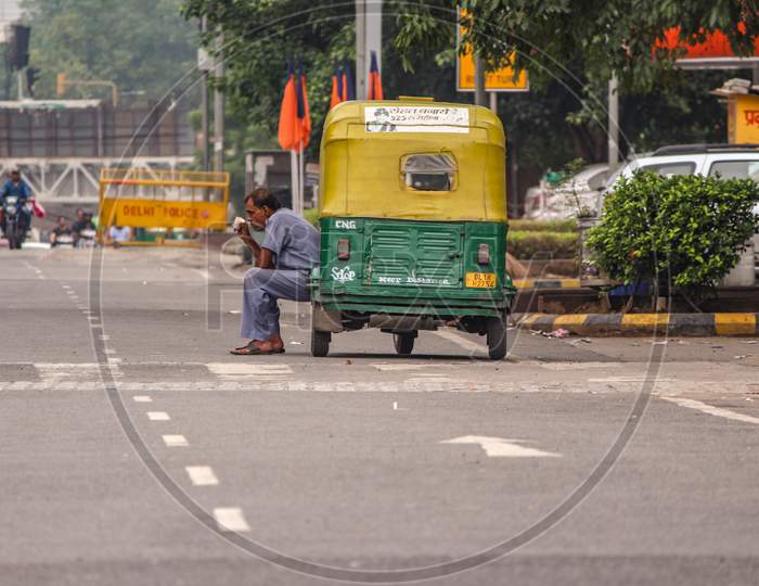 New Delhi, Delhi/ India - June 9 2020: A Auto Rickshaw Driver Sitting Outside His Auto In The Hot Weather In Delhi
