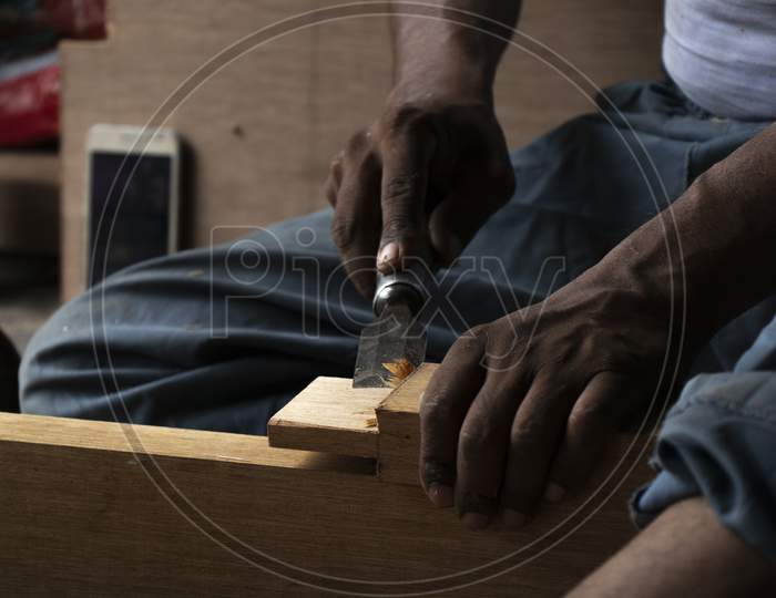 Carpenter Working With Gouge On Table In His Workshop