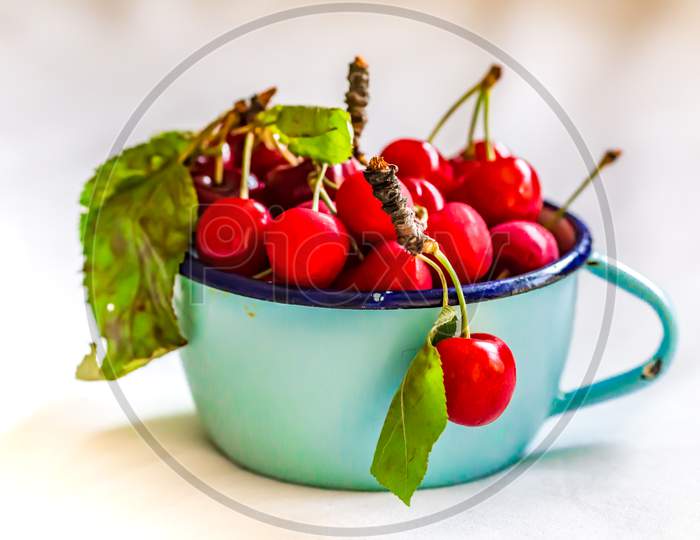 A shot of fresh cherries with green leaves on the smooth surface