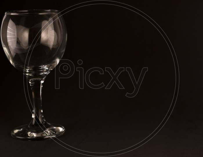 picture of empty wine glass on a black background and empty space for text.