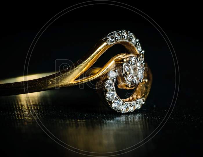 Macro Shot Of A Golden Diamond Ring In A Dark Background. Side View