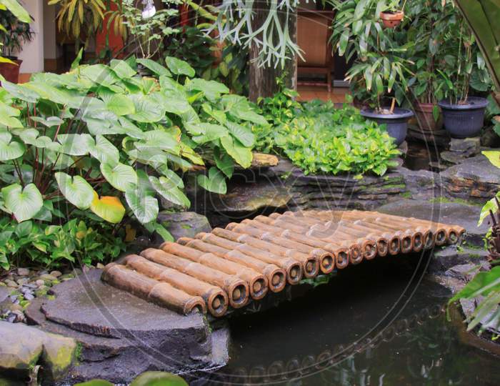 Bamboo Bridge Over Pond In Patio Garden Design
