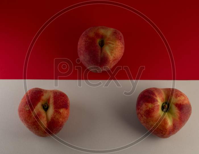 Juicy red peach on a red and white background. Photo has empty space for text.