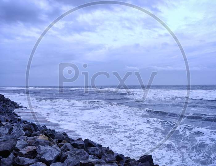 A Picture Of Beach With Rocks On The Shore And Cloudy Sky On Background. The Sea Is Violent With Strong Waves In This Picture. Kappil Beach (Varkala Town), Kerala.