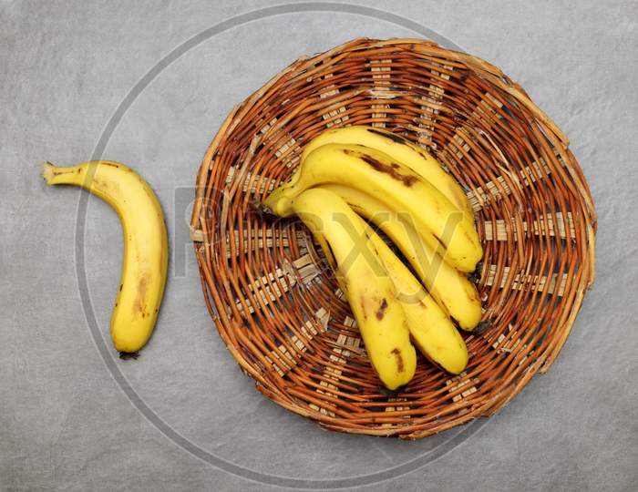 Bunch of Bananas in a wooden basket with grey background