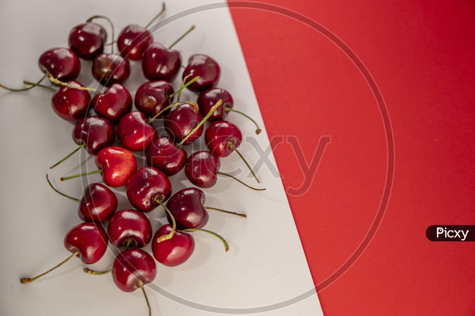 Fresh red cherries on a red and white background. Photo has empty space for text.