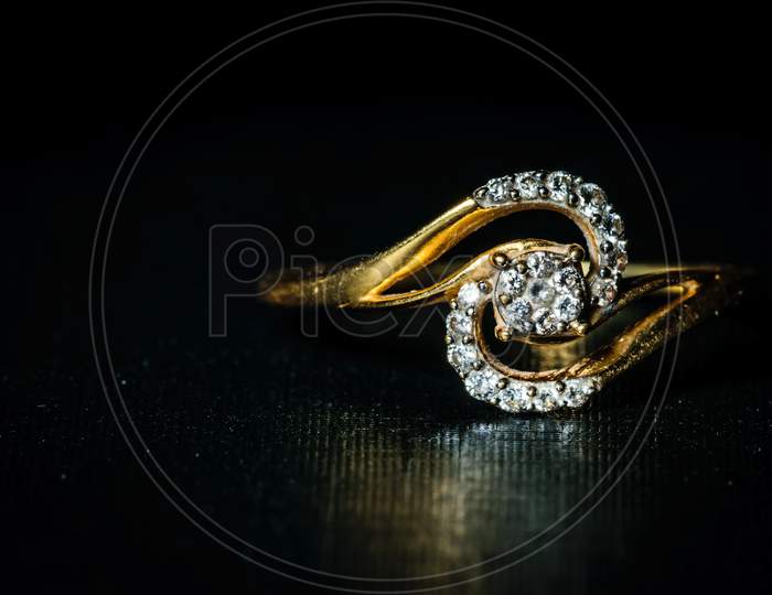 Macro Shot Of A Golden Diamond Ring Kept In The Right In A Dark Background. Space For Text In The Left