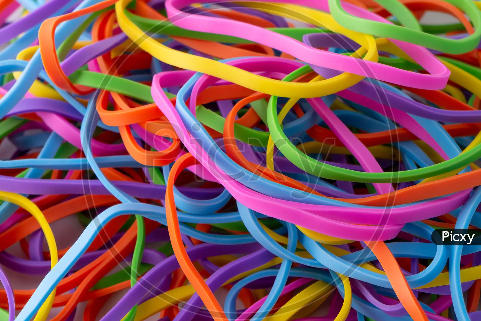 Bright neon rainbow rubber bands pile close up