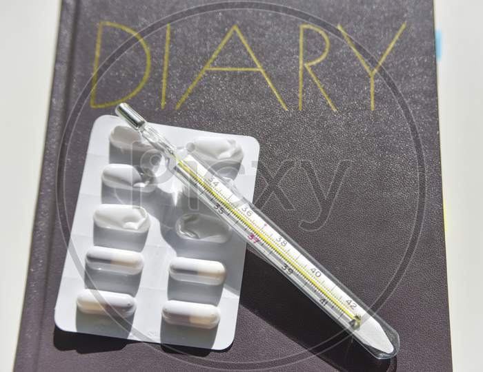 Selective Focus Of The Diary With Thermometer And Pills On The Background