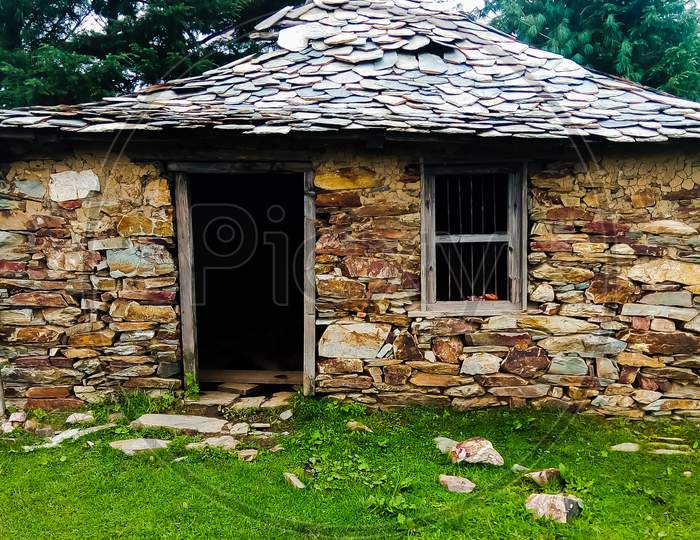 A ruined stone built and slate roofed hut in the middle of the forest in Himachal Pradesh India