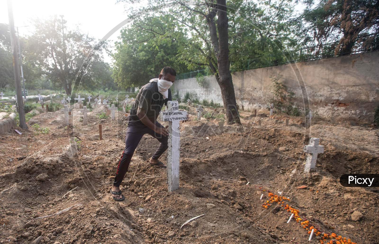 A Cemetery Worker Fixes A Cross Over Newly Dug Graves At Mangolpuri Cemetery Amid The Covid-19 Pandemic On July 1, 2020 In New Delhi, India.