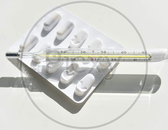 Isolated Thermometer And Pills On The White Background